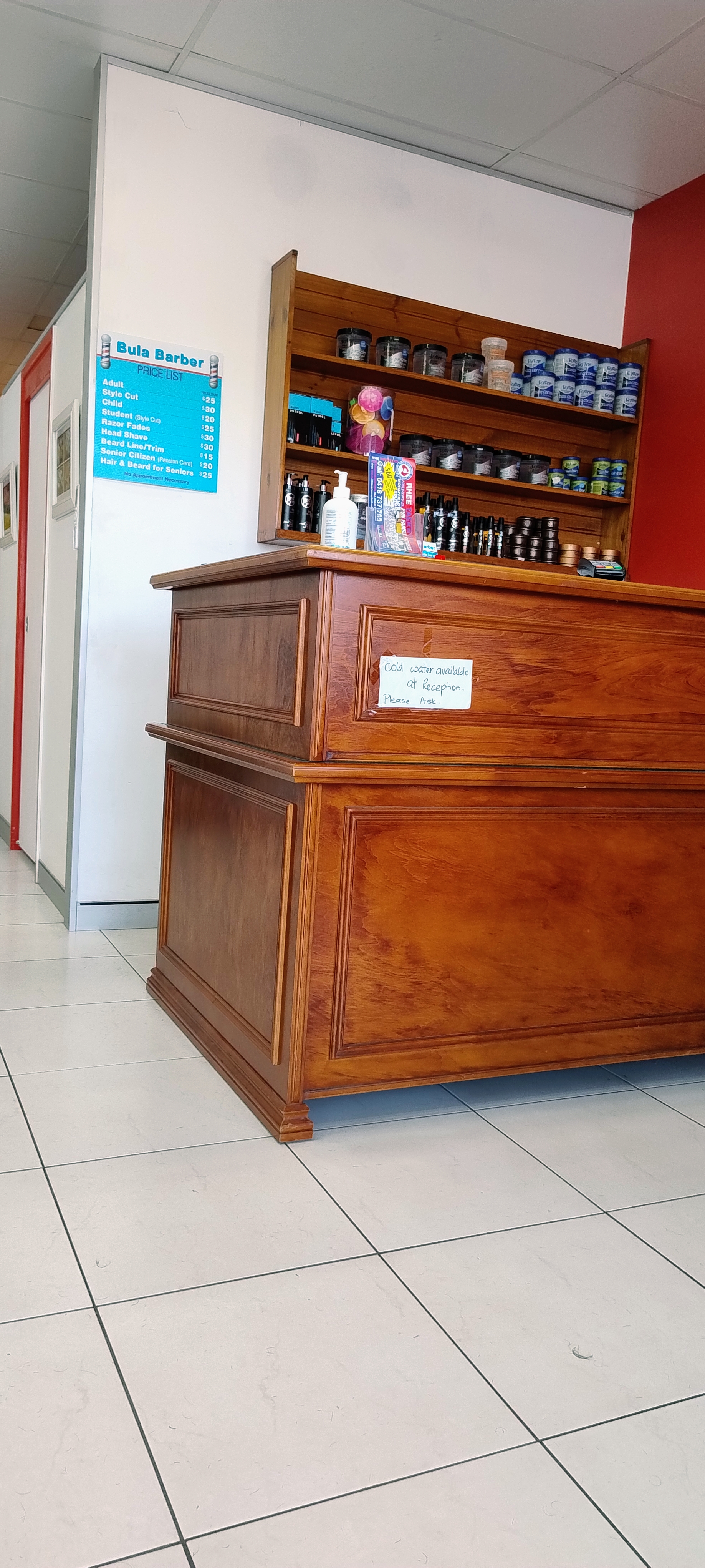 Inside the shop, the timber reception counter and the price board on the wall
