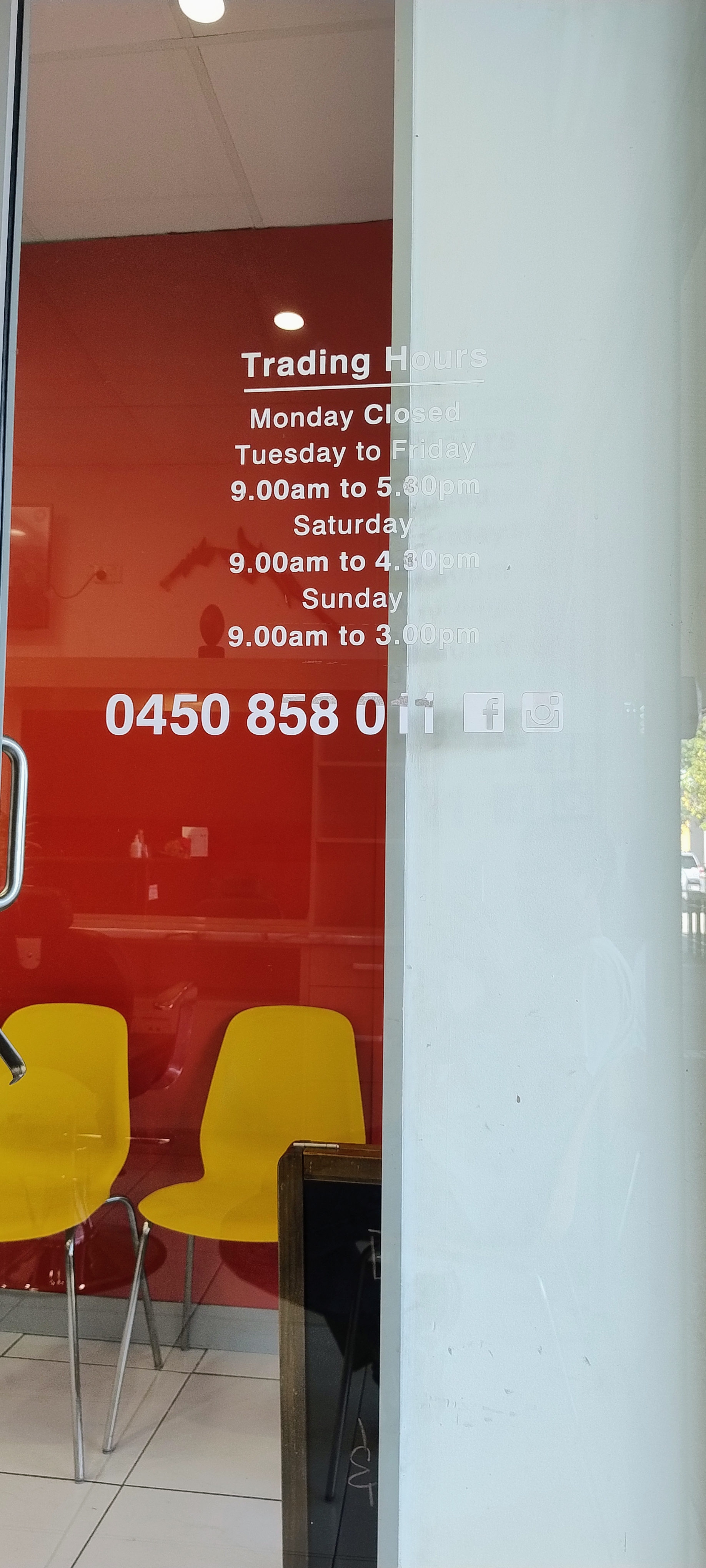 The shop door, with trading hours and the phone number on the glass